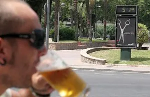 Un joven bebe una cerveza frente a un termómetro. /RAFA FRANCÉS/AGM