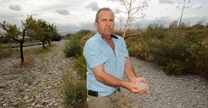 José Sánchez muestra un puñado de tierra en la zona de su finca que dice tener abandonada por la contaminación de aguas residuales del polígono. ::                             PACO ALONSO / AGM