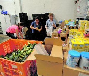 Tres voluntarias colocan alimentos en el almacén de Cáritas en el barrio de La Viña. :: Paco Alonso