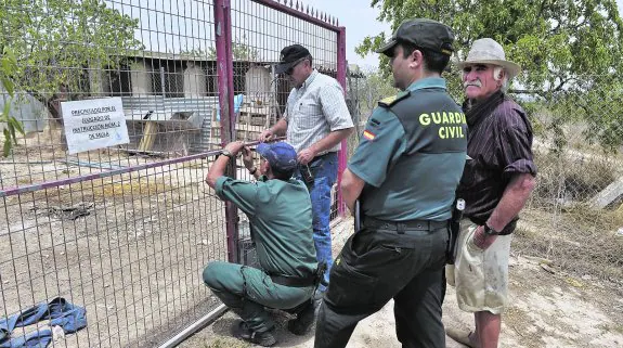 Los agentes del Seprona clausuran la finca tras la actuación ante la atenta mirada del dueño, tocado con un sombrero. 