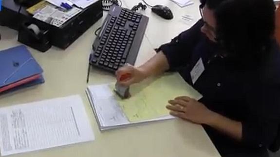 Una funcionaria sella el documento de entrada de las firmas.