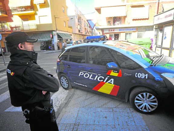 Un agente de la Policía Nacional, junto a un coche-patrulla. 