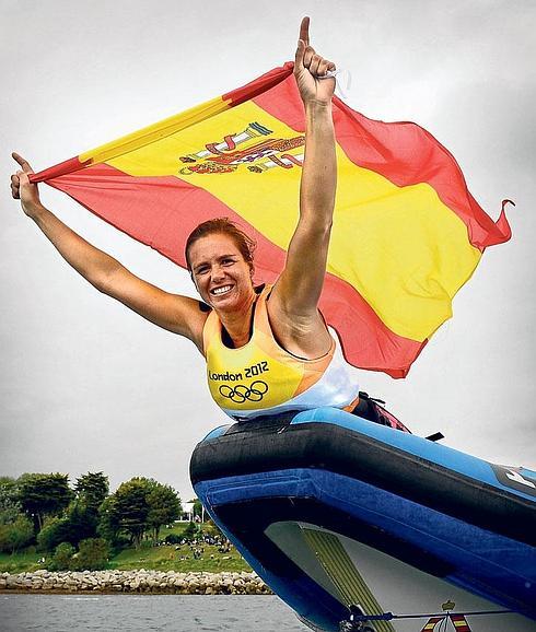 Marina Alabau ondea la bandera española sobre la proa de una gomona tras conquistar el oro en RS-X (wind surf) en los Juegos Olímpicos de Londres.