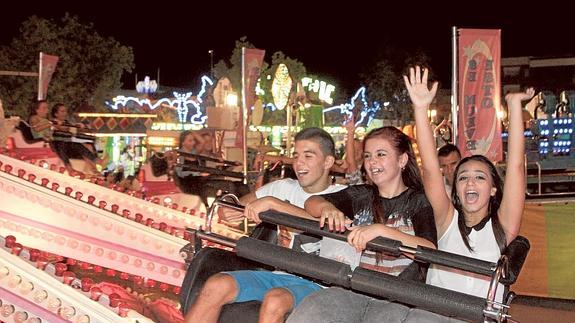 Tres amigos se divierten en una de las atracciones del recinto del Huerto de la Rueda, que anoche abrió sus puertas.