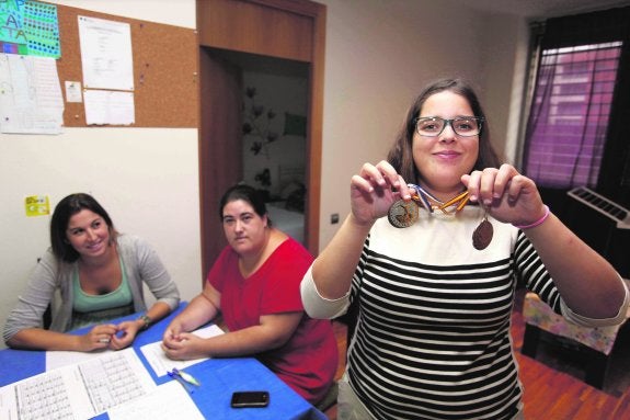 Marta muestra sus medallas de natación, en presencia de Eva -la mediadora- y Lorena. AGM