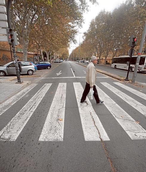 Un hombre cruza por un paso de cebra sobre el firme agrietado del Paseo de Alfonso XIII. 