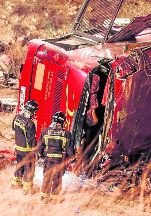 Dos bomberos observan el autobús siniestrado. 