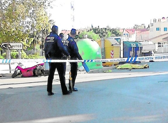 Dos policías ante el cadáver y la moto del accidentado. 