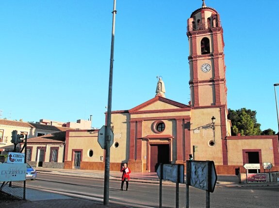 Una mujer, al atardecer frente a la iglesia parroquial de La Palma. 