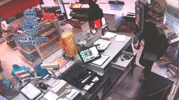 Captura del vídeo de seguridad de una de las gasolineras que muestra a uno de los atracadores abriendo la caja registradora y portando un arma. 
