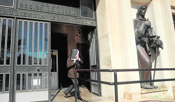 «No quiero protagonismo». El magistrado Manuel Abadía se cubre el rostro con un portafolios, ayer, cuando abandonaba el Palacio de Justicia después de dictar la resolución contra el expresidente de la Comunidad, Ramón Luis Valcárcel. 