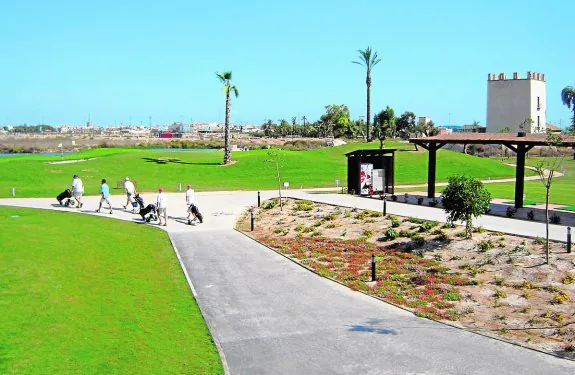Varios jugadores se disponen a utilizar el campo de golf. Al fondo, la urbanización. :: A. SALAS