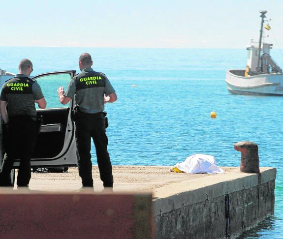 Dos agentes de la Guardia Civil, junto al cuerpo del submarinista en el puerto de La Azohía. 