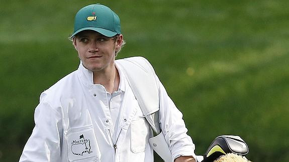 El cantante irlandés Niall Horan del grupo One Direction lleva la bolsa del golfista de Irlanda del Norte Rory McIlroy