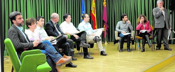 La silla reservada al PP, que quedó vacía; el candidato del PSOE Joaquín López, la candidata de Ganar la Región Esther Herguedas, el candidato de UPyD Rubén Serna, el candidato de Podemos Felipe Iracheta, el candidato de Ciudadanos Juan José Molina, el candidato de VOX Sergio Lucas; y los moderadores del debate, Manuel Madrid, de 'La Verdad'; y Lola García, de 'La Opinión'. 