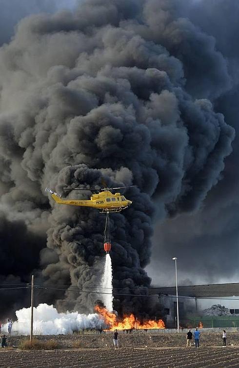 A la izquierda, vecinos de la zona siguen de cerca el trabajo de los bomberos para tratar de extinguir el fuego