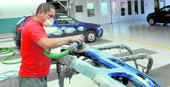 Un mecánico pinta el paragolpes de un vehículo en un taller de Murcia, en una imagen de archivo. 