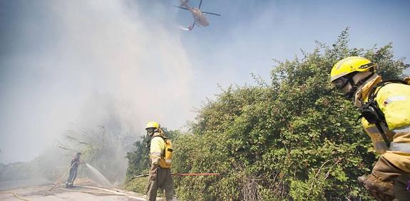 Efectivos de Bomberos trabajando ayer, con la ayuda del helicóptero de Emergencias, en la extinción del incendio registrado en una parcela de Barriomar. 