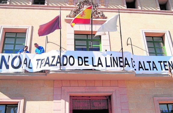 Dos trabajadores colocan la pancarta contra el proyecto eléctrico en el Ayuntamiento de Totana. 