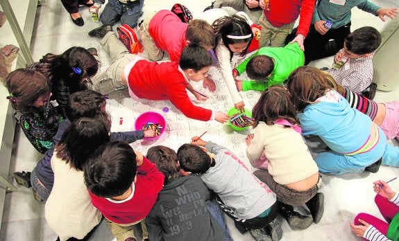 Un grupo de niños colorea una sopa de letras, durante un taller infantil. 