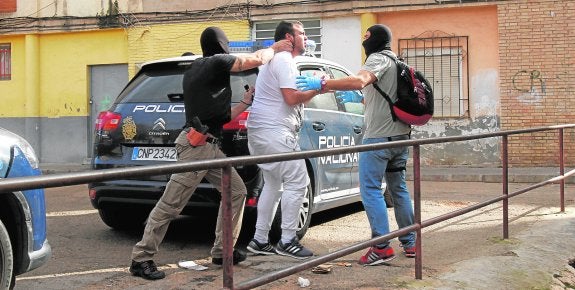 Arriba, dos policías trasladan a un detenido en Lo Campano. A la derecha, funcionarios sacan bolsas con marihuana de un piso.
