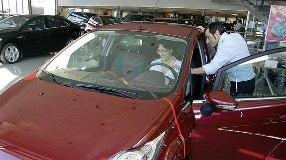 Un vendedor enseña un coche a una compradora. 