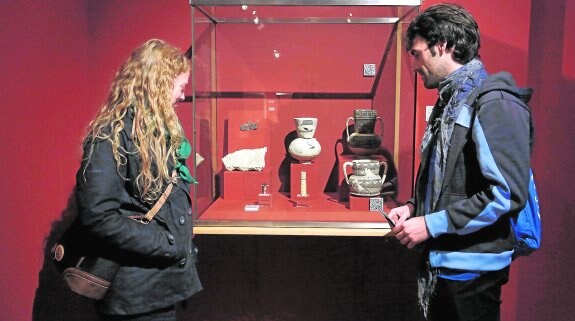 Dos jóvenes observan varias de las piezas expuestas en la muestra sobre Begastri que exhibe actualmente el Arqueológico de Murcia. 