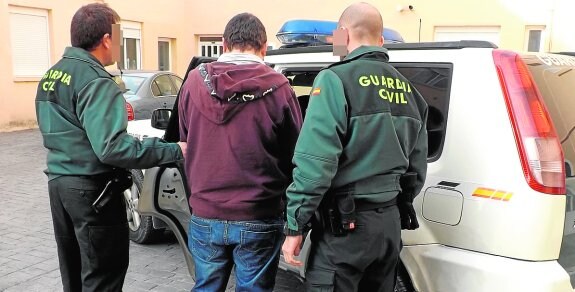 Dos agentes introducen al presunto atracador en un coche patrulla para su traslado al juzgado.