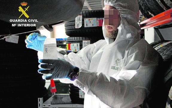 Recogida de muestras. Un agente de la Policía Científica de la Guardia Civil, ayer, examinando el vehículo implicado en el atropello en Alquerías. 