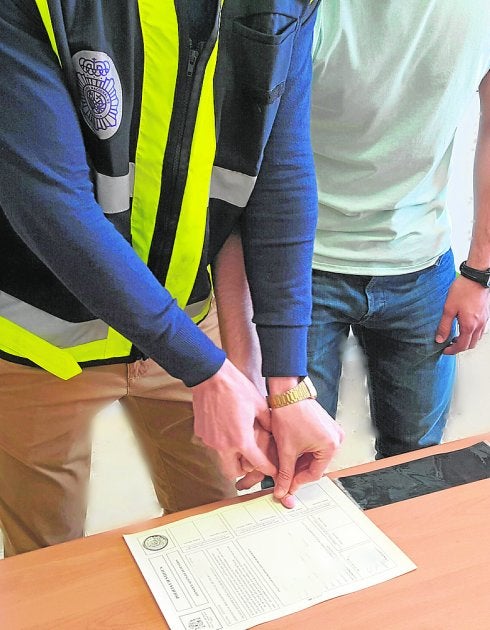 Un agente toma las huellas dactilares a uno de los detenidos. 