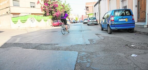 Un ciclista sortea los remiendos del firme en la calle Jardines de Los Dolores. 