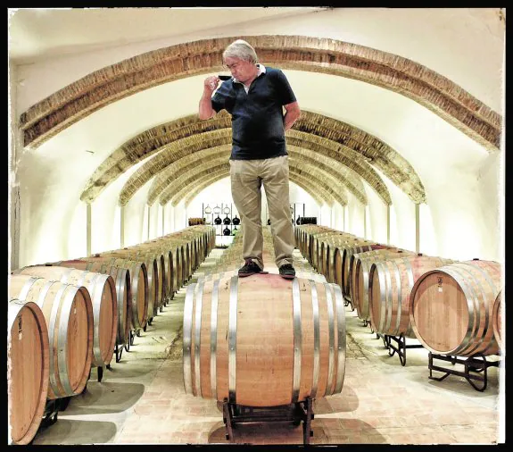 Agapito Rico cata uno de sus vinos (El Sequé) subido a uno de los barriles de su bodega de Pinoso (Alicante).