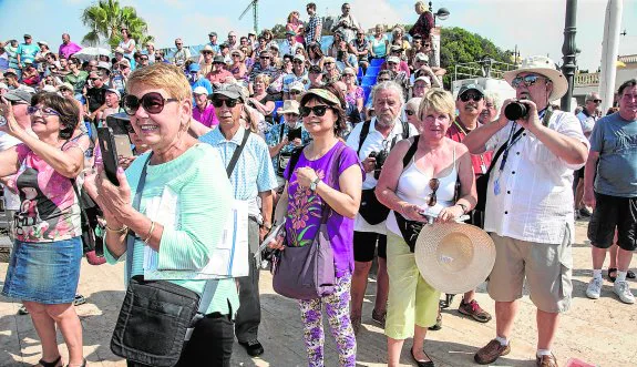 Decenas de turistas en la explanada del puerto, algunos de ellos subidos a las gradas, durante un momento del Desembarco de la Armada Romana. 