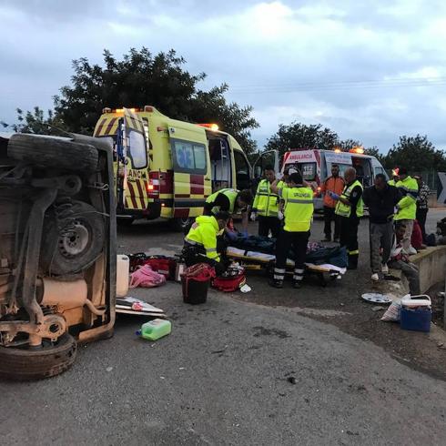 Los sanitarios atienden a un herido al lado del coche volcado. 