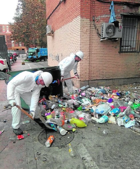 Dos operarios, ayer, retirando con palas la basura acumulada junto a uno de los edificios.