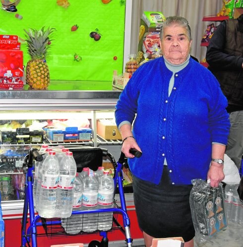 Pilar, vecina de Abarán, ayer, carga con dos cajas de agua embotellada en su andador.