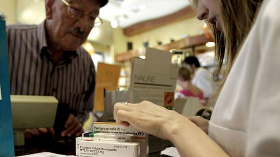 Un pensionista adquiere medicamentos en una farmacia. 