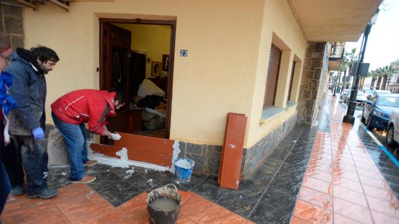 Vecinos de Los Alcázares colocando ayer tablachos en sus casas para impedir la entrada de agua. 