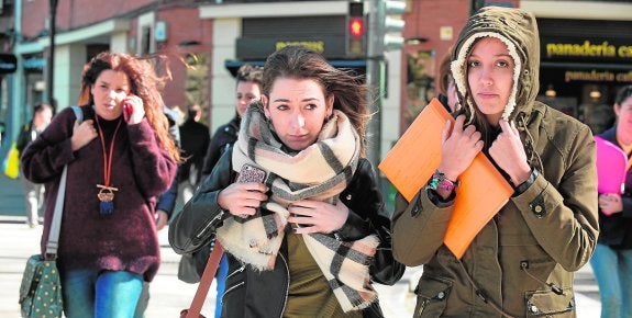 Dos jóvenes se protegen de las rachas en Murcia.