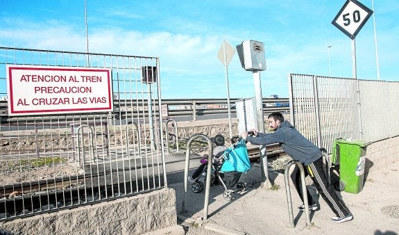 Un hombre se dispone a cruzar el paso a nivel del Feve en Los Mateos, llevando consigo un niño en un carrito, ayer a mediodía.