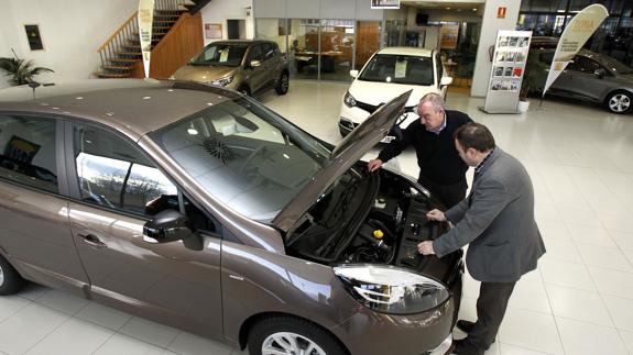 Un comercial inspeccionando un coche con el comprador.