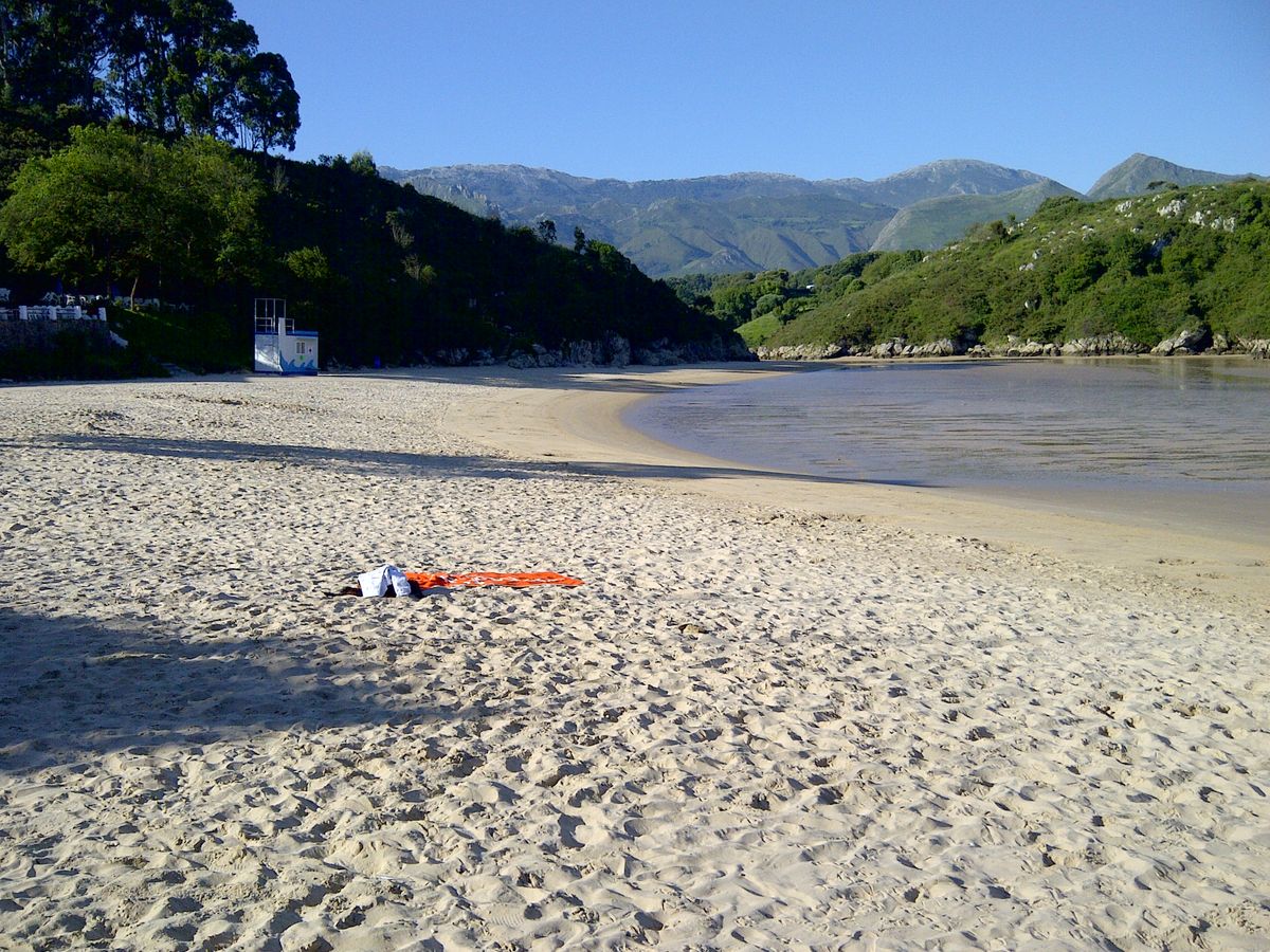 11 Playa de Poo (Llanes). Rodeada de verdes praderas y rocas, sus aguas color esmeralda están resguardadas entre acantilados, lo que la convierte en un lugar idóneo para que los niños jueguen sin peligro alguno. Desde la playa se puede divisar el famoso islote de castro de Poo, una peculiar formación rocosa con forma de barco hundido.