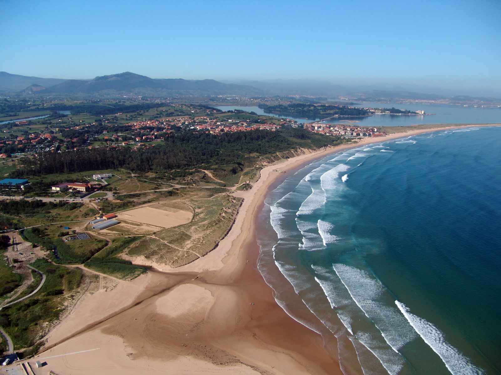 Playa de Somo. Una kilométrica playa de arena fina y aguas cristalina. La favorita de los surfers de la zona, que gracias a su fuerte oleaje es idónea para la práctica de este deporte. También es perfecta para un agradable día familiar, y es que su gran extensión permite alojar a numerosos visitantes sin que se produzca el efecto ‘lata de sardinas’.Sus vistas a la Bahía de Santander, la Península de la Magdalena y las islas del Mouro la convierten en uno de los destinos preferidos de los turistas que visitan Cantabria.