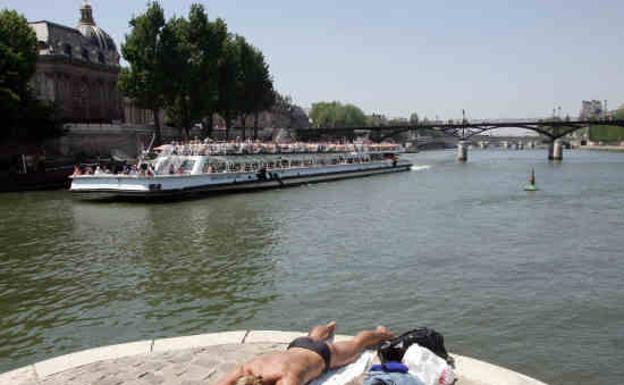 Un hombre toma el sol junto al río Sena, París, Francia. 