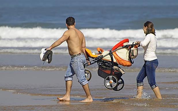 Una familia pasea por la playa. 