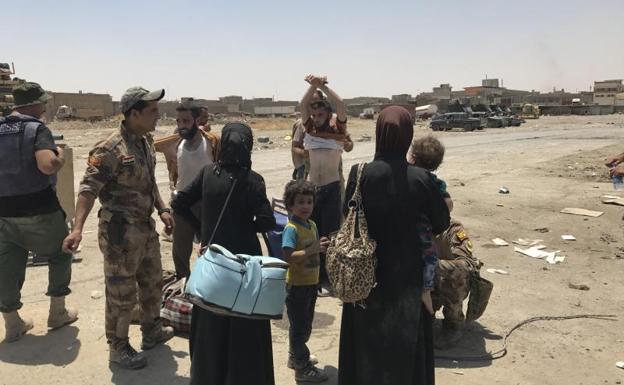 La policía registra a un grupo de civiles que huyen de Mosul.