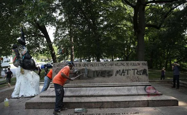 Empleados públicos borran los escritos en una de las estatuas retiradas en Baltimore.