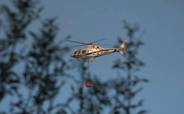 Helicóptero transportando agua para apagar el incendio. 