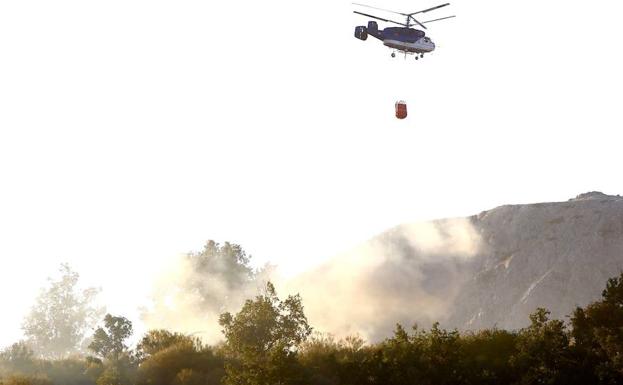 Un helicóptero trata de socorrer las llamas.
