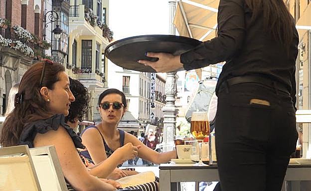 Un camarero atiende a sus clientes en el centro de León.